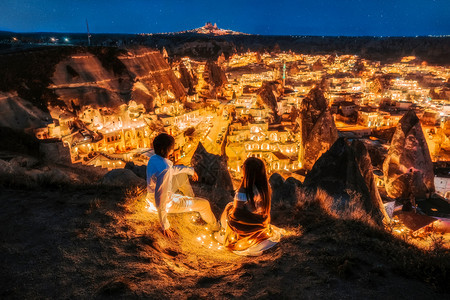 景观亚裔情侣在乌奇萨戈尔梅日落景点UchisarGoreme的爱和夜视中游客编队图片
