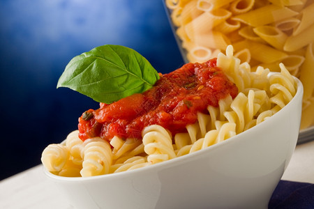 照片美味的意大利面和蓝底番茄酱福格利亚莎大蒜图片