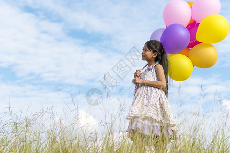 白色的美丽快乐可爱女孩拿着气球在绿色草地白云和蓝天空上运行快乐的天空手拿着充满活力的空气球在生日派对上玩欢乐的可爱女孩阳光图片