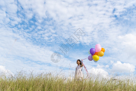 白色的明亮快乐可爱女孩拿着气球在绿色草地白云和蓝天空上运行快乐的天空手拿着充满活力的空气球在生日派对上玩欢乐的可爱女孩子图片