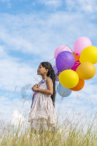 自由快乐的可爱女孩拿着气球在绿色草地白云和蓝天空上运行快乐的天空手拿着充满活力的空气球在生日派对上玩欢乐的可爱女孩子跑步图片