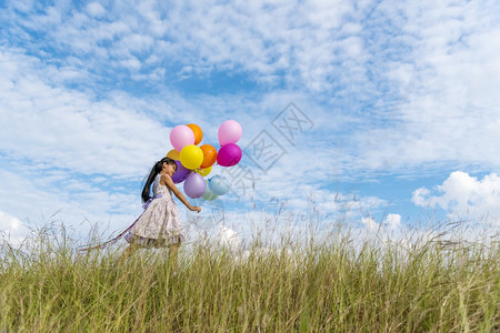 乐趣快的可爱女孩拿着气球在绿色草地白云和蓝天空上运行快乐的天空手拿着充满活力的空气球在生日派对上玩欢乐的可爱女孩传播外部图片