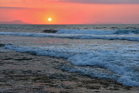 海岸美丽的夏天日落在海滩上惊人的景色与海浪和太阳反射背景假期和度旅行的背景希腊克里特岛黄色的早晨图片