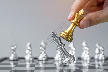 赢在棋盘竞争战略成功管理商业规划中断和领导力概念期间商人用手搬运金牌象棋王人物和格斗士或对手的实战人数保持金子图片