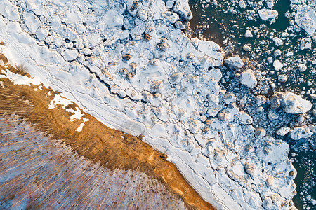 美丽湖岸的顶端风景湖面上露着树木雪石和水中的冰追踪排背景图片