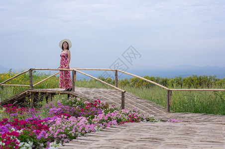美丽的身着自然花美丽女子她穿着白色礼服和红帽子在泰国兰芒省MaeMohCoalMine的TungBuaTong墨西哥向日葵田上穿图片