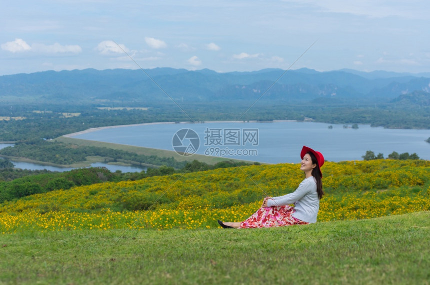 莫黄色的身着自然花美丽女子她穿着白色礼服和红帽子在泰国兰芒省MaeMohCoalMine的TungBuaTong墨西哥向日葵田上图片