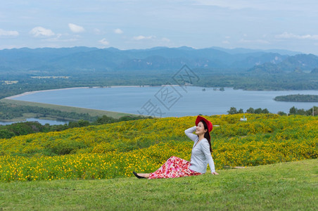 身着自然花的美丽女子她穿着白色礼服和红帽子在泰国兰芒省MaeMohCoalMine的TungBuaTong墨西哥向日葵田上穿白裙图片