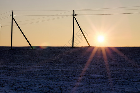 安装电线杆的田地日落期间冬季风景日落时的黄色天空风景日落时的冬天风景蒙供应下雪的图片