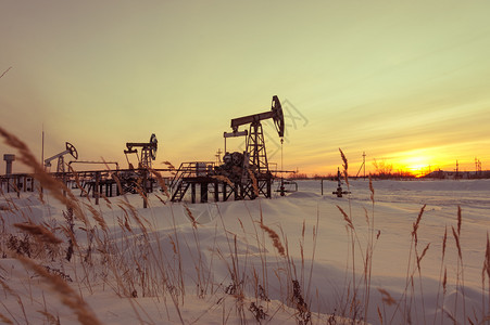 工具生态勘探油田上的泵千斤顶冬季日落天空背景石油开采概念调子泵千斤顶图片