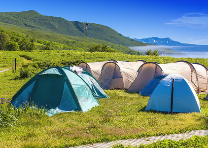 旅游者在山坡边湖岸的树林中扎营图片