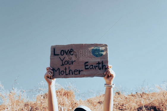 活动家种植园在蓝天气候变化概念的背景下手举拿着标语海报爱你的地球母亲爱你地球母亲横幅图片