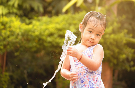 生长孩子们可爱的玩橡皮软管可爱小女孩在后院打喷水和阳光照射的儿童在炎热的夏日享受户外活动图片