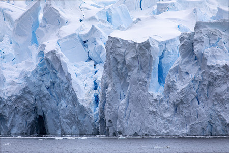 宽度在南极洲巨大的冰川舌中闪耀着黑暗的蓝洞穴裂缝和穿越海洋图片