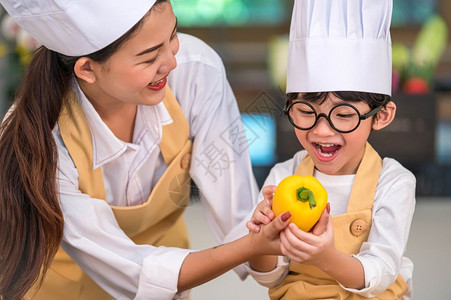 一顿饭感兴趣的喜欢做饭亚洲快乐小男孩主厨在家庭房里很搞笑的母亲烹饪人们的生活方式和家庭自制食物配料概念烤圣诞蛋糕和饼干并给人点餐图片