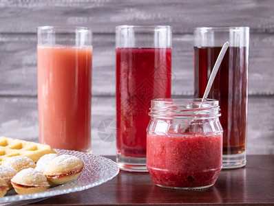 早午餐浆果靠近一碗饼干和罐果酱的玻璃杯中红汁一碗饼干和小罐果酱旁边的玻璃杯中红汁服务图片