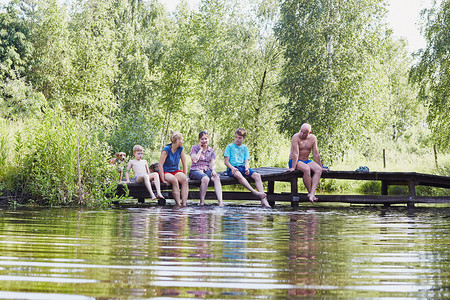 木头花园家庭一起时间坐在湖边的桥上与自然相近的树木之间在暑假期Candid人真实时刻情况中朋友图片