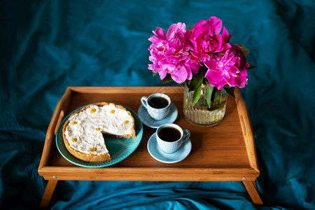 夏天舒适美丽的早晨香草芝士蛋糕咖啡蓝色杯子玻璃花瓶中的粉色牡丹美丽的早晨香草芝士蛋糕玻璃花瓶中的粉色牡丹蓝图片