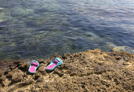 场景在亚得里海滩拖鞋透明水域附近的一块海石上在透明域附近的一块石头上躺着子而光亮的绿宝石色的沙滩妇女则躺在一条海边上闲暇明亮的图片