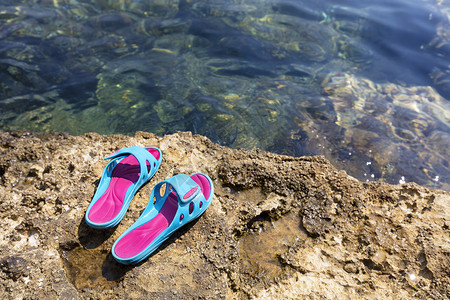 结石概念的粒状在亚得里海滩拖鞋透明水域附近的一块海石上在透明域附近的一块石头上躺着子而光亮的绿宝石色的沙滩妇女则躺在一条海边上图片