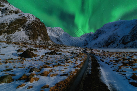 通向高山的美丽道路由北光或AuroraBorealis挪威冬季美丽的山地风景挪威斯堪的纳维亚冬季和挪威斯堪的纳维亚缰绳屋北极星图片