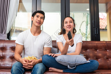 技术观看亚洲夫妇在家乡沙发上一起看电视以及度假与节日概念蜜月及婚礼前主题情人节快乐家庭活动等生方式概念在华伦士节愉快的家庭活动假图片