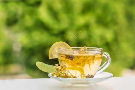一杯热茶在木板上打麻布和茶叶种植园背景上打麻布一杯热茶在木桌上打爆红茶春天维生素蜜糖图片