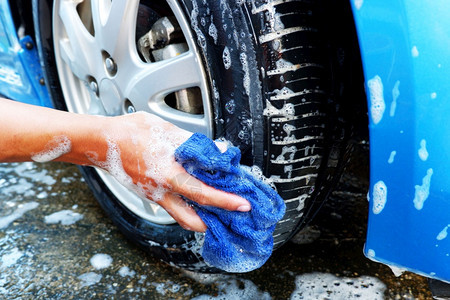 在洗车时用微纤维布清洗汽车轮子湿的缘干燥图片