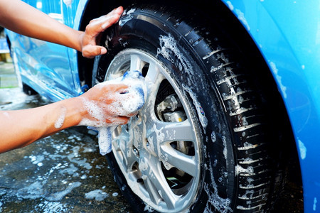 男人在洗车时用微纤维布清洗汽车轮子手磁盘图片