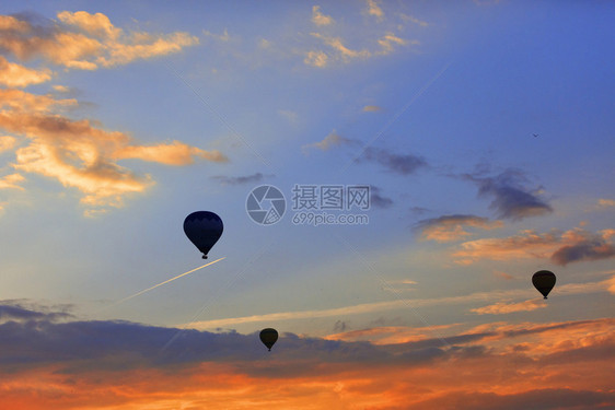 日出清晨在空中高飞行的机背景下将游客带入蓝色天空的气球休眠机使游客登上烈红云空的蓝天月光下的气球休眠机其背景是早晨的天空其中含有图片