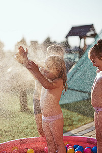 清爽小可爱的孩子享受着凉水由父亲喷洒在炎热的夏日后院Candid人真实的时刻情况溅起冷却图片
