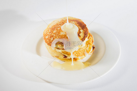 烹饪早餐棕色的煎饼堆在白盘子上薄饼加了甜的浓缩牛奶图片