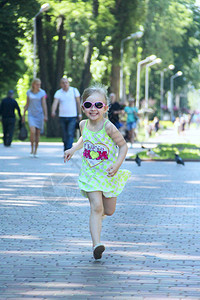 情绪快乐的小女孩在城市公园奔跑积极的幼稚排放模糊好的图片