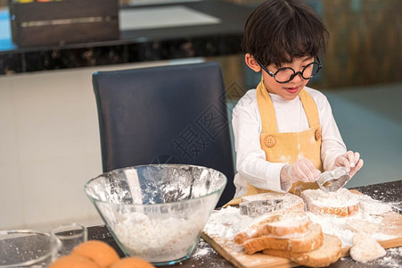 面包店喜欢烘烤的亚洲小快乐男孩在家厨房里很滑稽人们的生活方式和家庭自制食物原料概念烤圣诞蛋糕和饼干人们的生活方式和家庭自制食品成图片