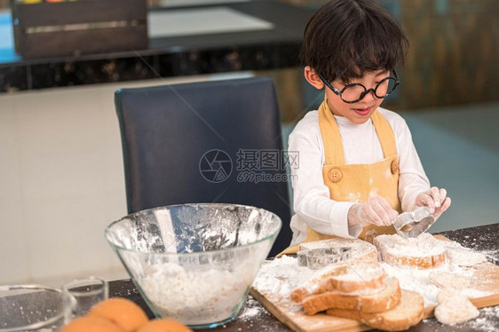 面包店喜欢烘烤的亚洲小快乐男孩在家厨房里很滑稽人们的生活方式和家庭自制食物原料概念烤圣诞蛋糕和饼干人们的生活方式和家庭自制食品成图片