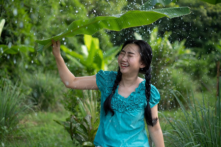 乡村蓝色的自然在绿花园背景下雨时一位年轻亚洲女身着香蕉叶的黑头发肖像图片