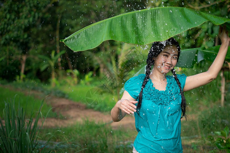 女孩新鲜的在绿花园背景下雨时一位年轻亚洲女身着香蕉叶的黑头发肖像愉快图片