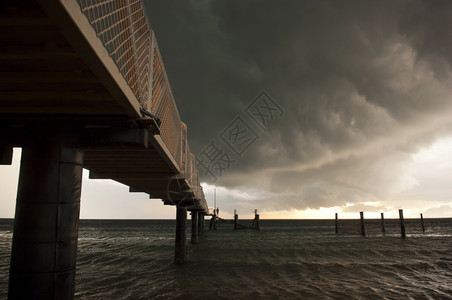 海浪巨大的黑风暴云聚集起来人们在码头上钓鱼泊位一种图片