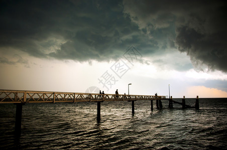 离开地平线巨大的黑风暴云聚集起来人们在码头上钓鱼图片