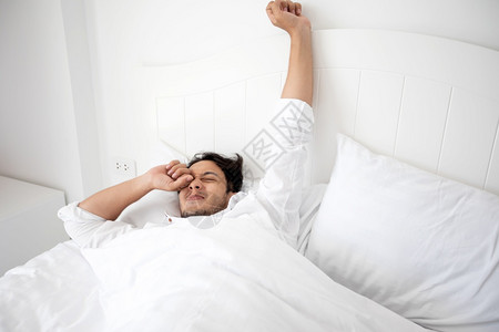 成人钟一个男醒来时躺在床上完全休息早上打开窗帘呼吸新鲜的空气得到图片