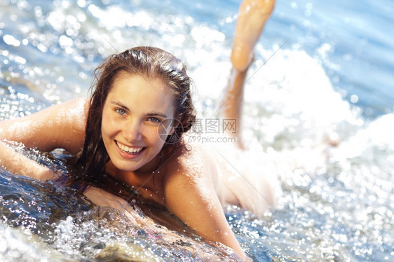 热带溅年轻棕色女人躺在前面冲浪时泼水日光浴图片