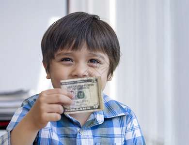 银行业有选择焦点快乐小学生显示五美元男孩子持有钞票捐款或储蓄资金的未来小男孩得到了钱捐款的未来小男孩得到的钱生商业图片