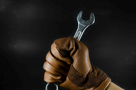 暗光下皮手套男握着扳警卫维护钥匙图片素材