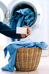 服饰名片烘干机服饰男子在装有洗衣机背景的洗涤机篮子衣服上持有空名片的人丝绸背景