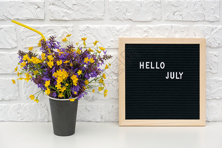 你好七月在黑色字母板上和一束彩色鲜花图片