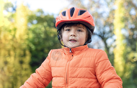 外部6至7岁的亚裔高加索混杂种族男孩穿着自行车头盔站在公园外面孩子在秋天的户外玩得开心YothumnChildFunter锻炼积图片
