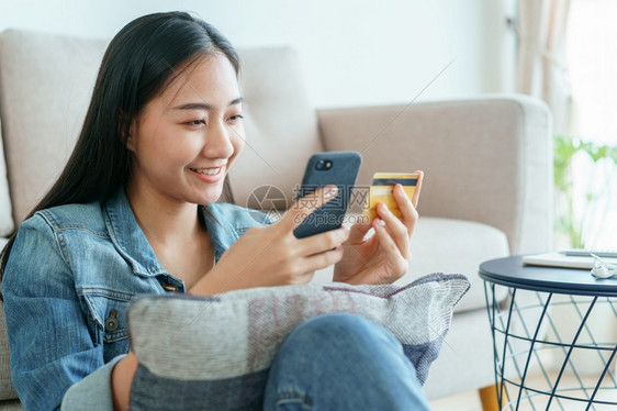 美丽的亚洲年轻女在网上用家里的信卡购买妇女正在使用智能手机并进行在线交易概念即通过技术和生活方式在网上购物这是新的常态a利用智能图片