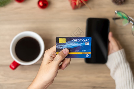 十二月在12圣诞快乐夜12月季节黑星期五销售新年和节假日概念期间手持信用卡于在线购买智能手机的网上购物家红色的图片