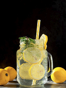 一杯加柠檬汁或莫吉托的杯子一加柠檬和薄荷饮料的鸡尾酒在黑色背景上黄的垂直茶点图片