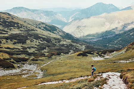 积极的运动带着背包在山上徒步旅行的年轻人积极度过暑假渡观看少年从山顶下到脚沿坡谷走下来的青少年穆戈图片